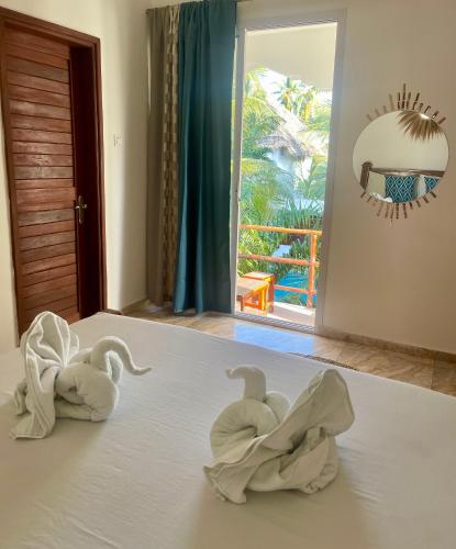 two towel swans sitting on top of a bed at Reyna Resort By Cezere The Palm in Paje