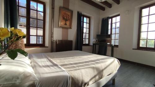 a bedroom with a bed in a room with windows at Le Champcevrais in Champcevrais