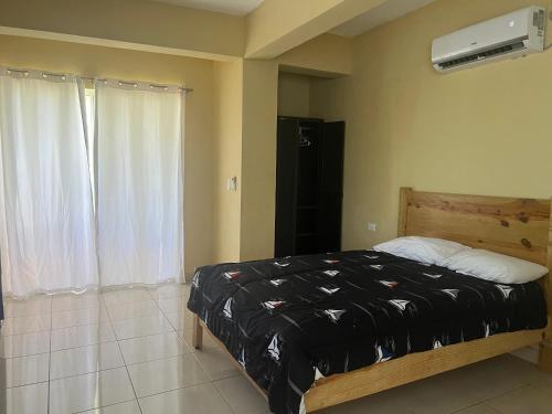 a bedroom with a bed with a black comforter at Plaza Real Resort in Juan Dolio