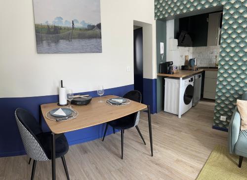 une salle à manger avec une table et des chaises et une cuisine dans l'établissement Appartement entier cosy, à Rouen
