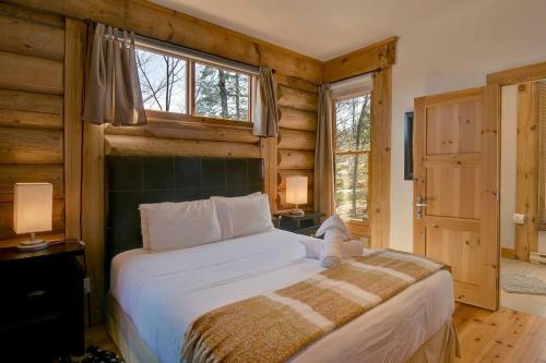 a bedroom with a large bed in a room with wooden walls at Luxurious Scandinavian Cottage with Private Jacuzzi in Lac-Superieur