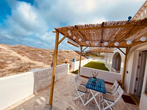 un patio avec une table et des chaises sous une pergola dans l'établissement La Juanita - Dosel, à Faro de Cullera