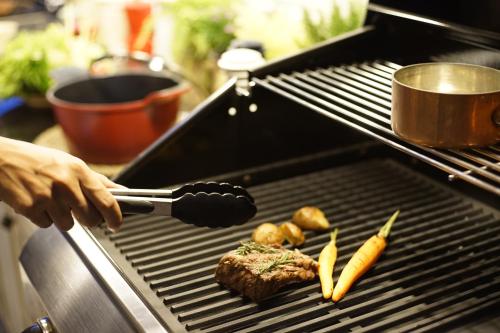 a person grilling meat and vegetables on a grill at Private Pool Villa 88 Nimman Chiangmai in Chiang Mai