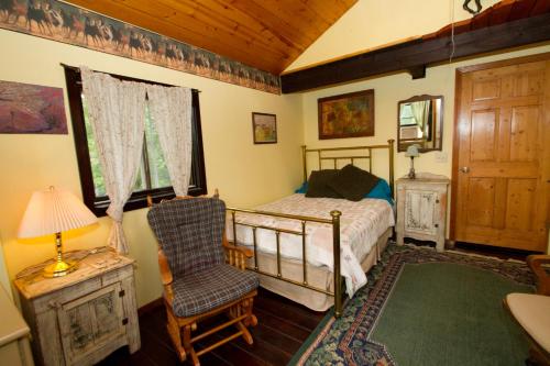 a bedroom with a bed and a chair and a window at White Horse Stable in Bayfield
