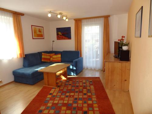 ein Wohnzimmer mit einem blauen Sofa und einem Tisch in der Unterkunft Pepis Ferienwohnungen inklusive Sommercard in Jerzens