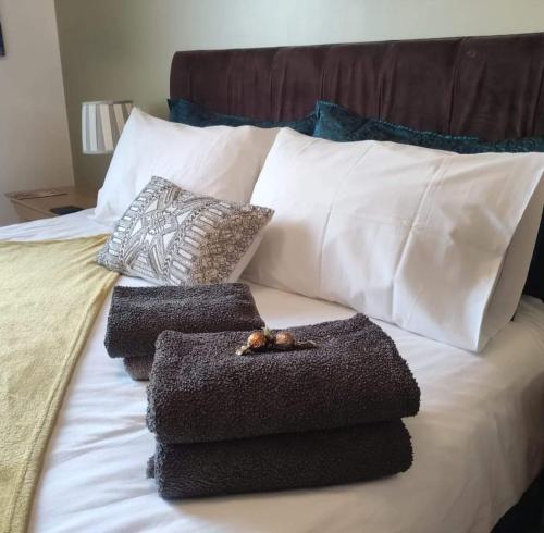a pile of towels sitting on top of a bed at Lovely 1 Bedroom Apartment in Plymouth