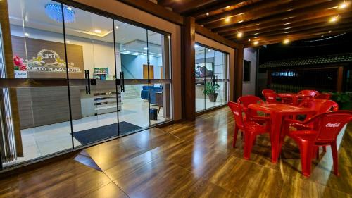 a dining room with red chairs and a red table at Conforto Plaza Hotel in Capitão Leônidas Marques