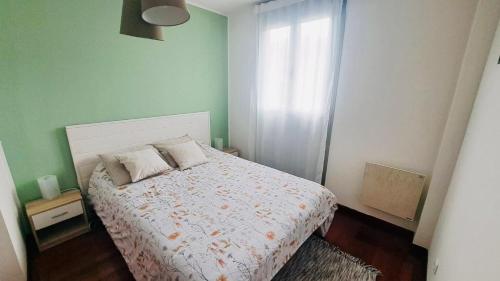 a small bedroom with a bed and a window at Elegante Adosado en Ampuero in Rasines