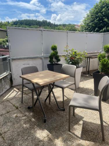 a wooden table and chairs on a patio at Hôtel les Jardins de Saulzet in Romagnat