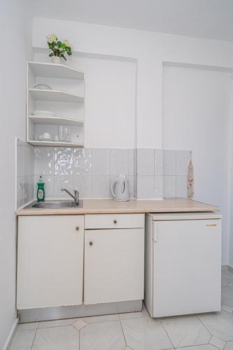 a kitchen with white cabinets and a sink at Fiore Di Mare Studios in Lassi