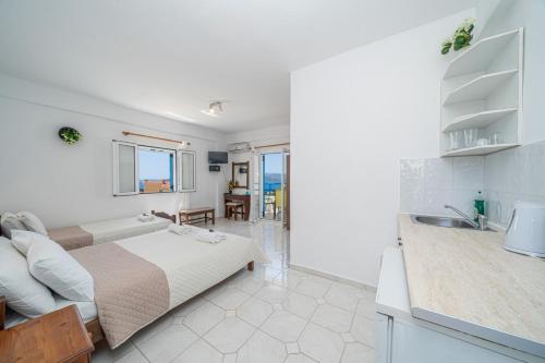 a white bedroom with a bed and a kitchen at Fiore Di Mare Studios in Lassi