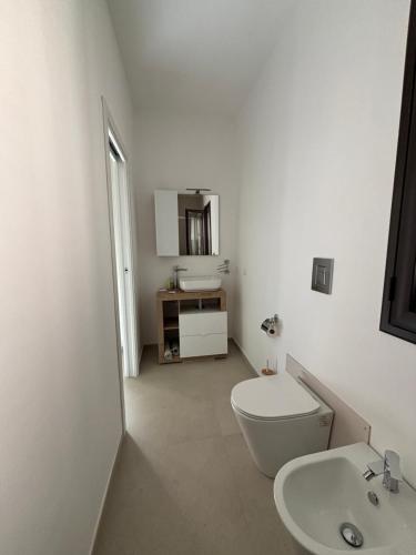 a white bathroom with a toilet and a sink at La Corte degli Scolopi in Palma di Montechiaro