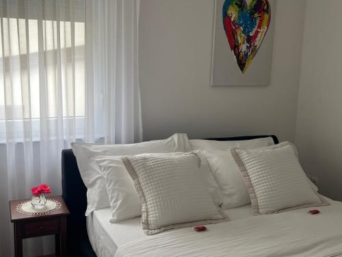 a bed with white pillows in a room with a window at Apartman My Choice in Bihać