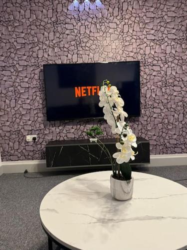 a table with flowers in front of a tv at 2 bed luxury apartment in Wolverhampton