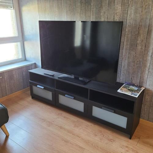 - un grand centre de divertissement noir avec une grande télévision à écran plat dans l'établissement Appartement place Keruscun, à Brest