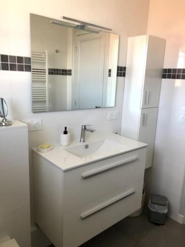 une salle de bain blanche avec un lavabo et un miroir dans l'établissement La Charmeuse à 500m de tout, à Arcachon