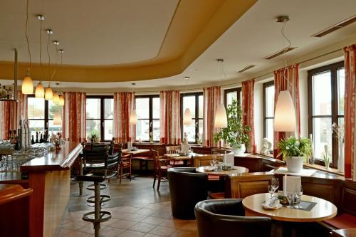 un restaurante con mesas, sillas y ventanas en Hotel & Restaurant Braunstein - Pauli´s Stuben, en Purbach am Neusiedlersee