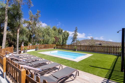 a swimming pool with lounge chairs in a yard at VV Finca El Toscalito in Arona