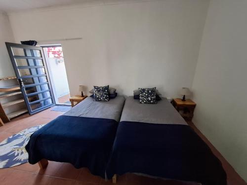 a bedroom with a large bed with blue and gray sheets at Farmhouse Guestrooms in Calitzdorp