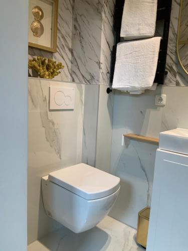 La salle de bains est pourvue de toilettes blanches et de murs en marbre. dans l'établissement Midcoast Studio TheBlue, à Nortorf