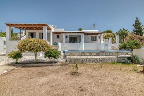 una casa bianca con piscina e alberi di Villa Manios Glisidia sea view a Kampos Paros
