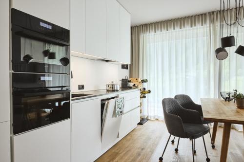 a kitchen with white cabinets and a table and a dining room at Stilvolles, lichtdurchflutetes Luxus-Appartement in der Residenz Silvretta - Inklusive Silvretta Card Premium in See