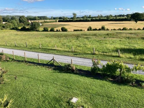 une route au milieu d'un champ avec une clôture dans l'établissement Aux portes d'Honfleur, à Fatouville-Grestain