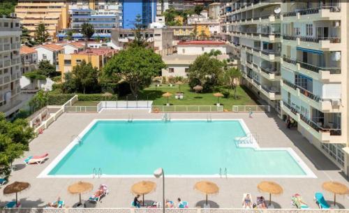 a large swimming pool with umbrellas in a city at Carihuela Beach in Torremolinos