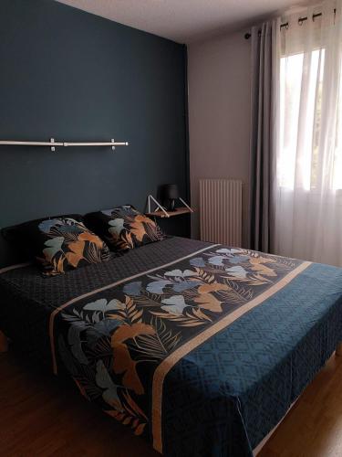 une chambre avec un lit avec une couverture bleue et une fenêtre dans l'établissement Alizé du lac, à Aix-les-Bains
