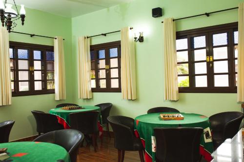 a room with green tables and chairs and windows at Hotel Fazenda Itáytyba in Tibagi