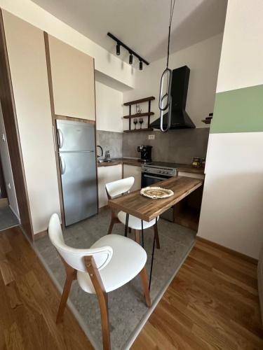 a kitchen with a wooden table and white chairs at Apartments Jana in Skopje