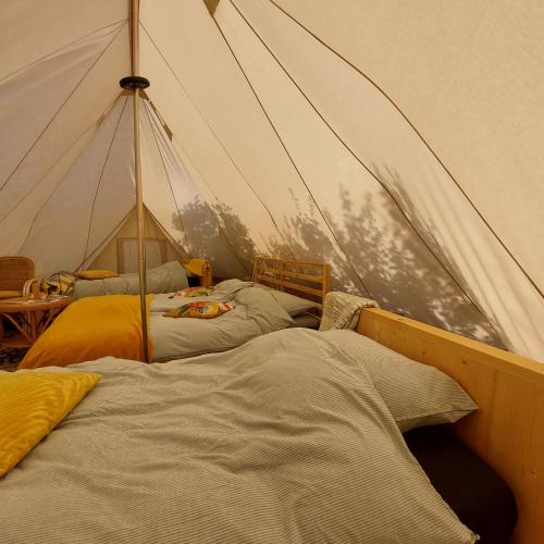 a bedroom with two beds in a tent at Bell tent Glamping Essenhof in Aagtekerke