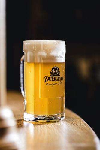 a glass of beer sitting on top of a table at Hotel Purkmistr in Plzeň