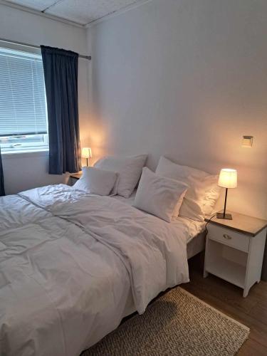 a bedroom with a bed with white sheets and a window at Haukeli hotell leilighet in Haukeligrend