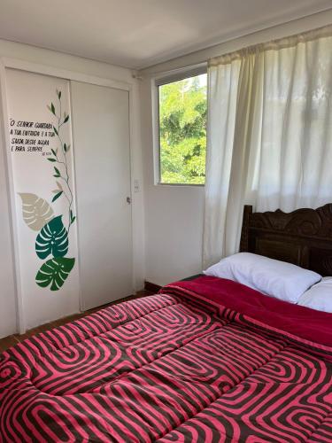 una camera da letto con un letto con una coperta rossa sopra di Pouso de Teria a Tiradentes