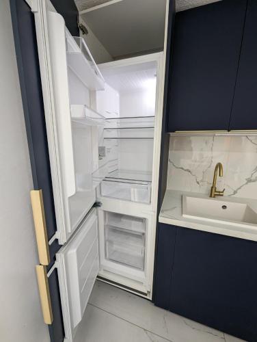 - un réfrigérateur vide avec une porte ouverte à côté d'un évier dans l'établissement Appartement T2 cabine, en bord de mer, WIFI et climatisation, à Saint-Cyprien