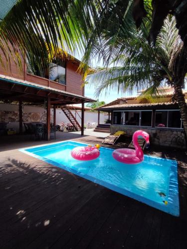 two pink inflatable flamingos in a swimming pool at Edícula acolhedora in Serra