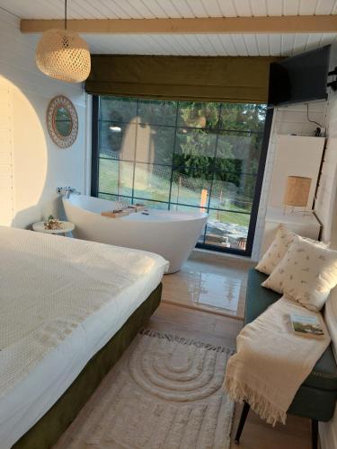 a bedroom with a tub and a bed and a window at Fancy Maisonnette in Gura Humorului