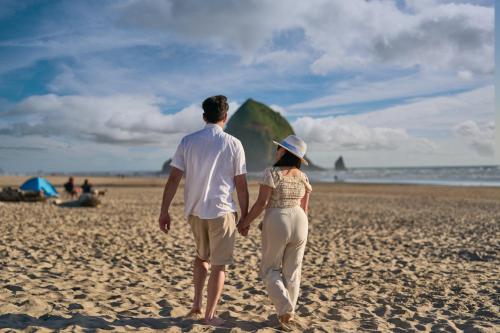 a man and woman walking on the beach with a kite at Surfsand Resort in Cannon Beach