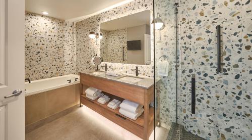 a bathroom with a sink and a mirror and a tub at Surfsand Resort in Cannon Beach