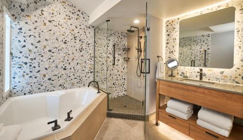 a bathroom with a tub and a sink and a mirror at Surfsand Resort in Cannon Beach