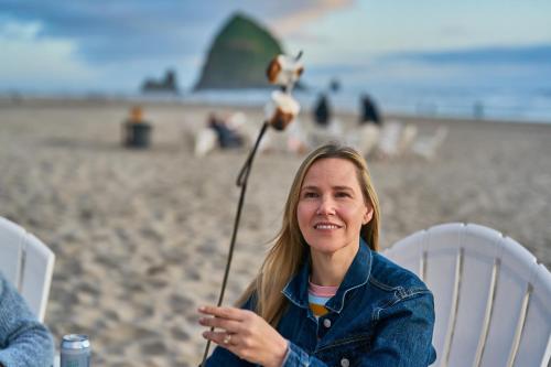a woman sitting in a chair on the beach at Surfsand Resort in Cannon Beach