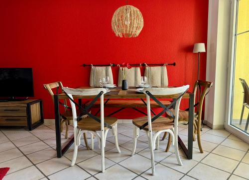 a dining room with a red wall and a table and chairs at Ferienwohnung Pracht - großzügige FeWo ab 75 qm in Rust