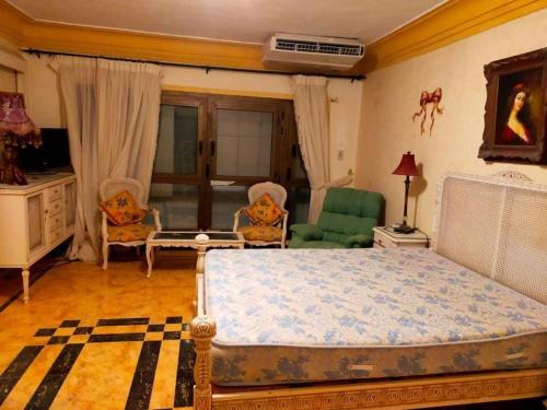 a bedroom with a bed and two chairs in it at Exquisite Vacation Home at Zomoroda Village - North Coast in Dawwār Shindī Fannūsh