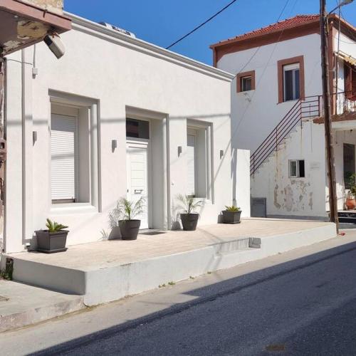 a white house with potted plants on a sidewalk at Casa d'oro 56 Living in Paradisi Rhodes in Paradeísion
