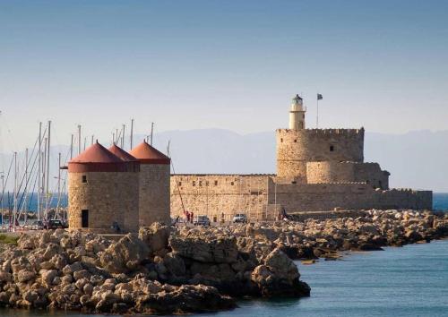 a castle with a lighthouse on a rocky island in the water at Casa d'oro 56 Living in Paradisi Rhodes in Paradeísion