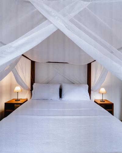 a bedroom with a white bed with two lamps at Vila Inca in Alto Paraíso de Goiás