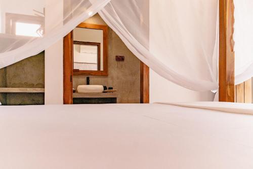 a bedroom with a white bed and a mirror at Vila Inca in Alto Paraíso de Goiás