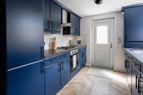 a kitchen with blue cabinets and a stove top oven at Homey 4 BR near the city Gateshead&Newcastle in Dunston