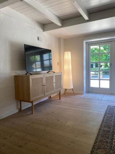 a living room with a flat screen tv and a dresser at Mindedalen - Idyl tæt på alt og helt i fred in Billum